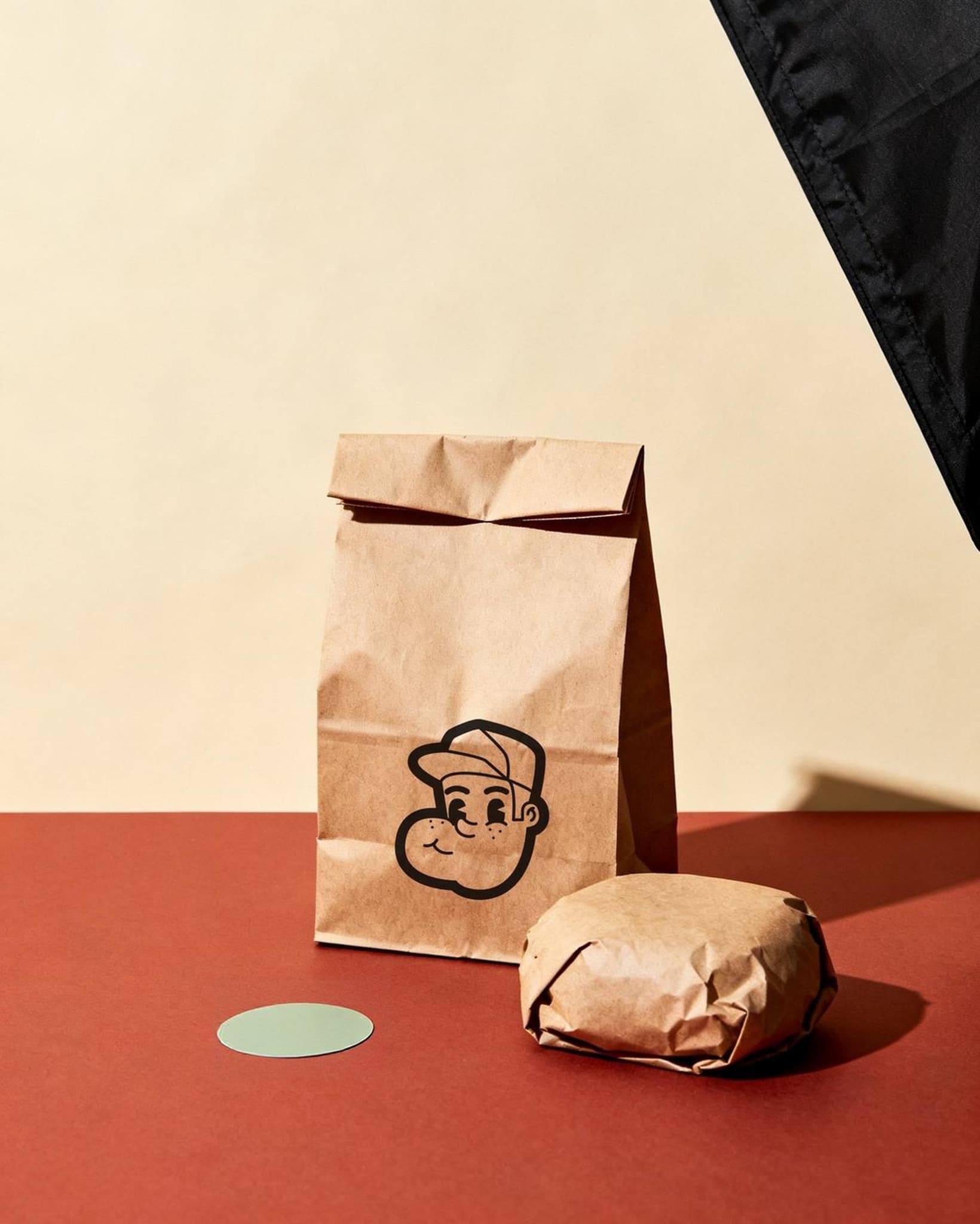 Sac kraft tamponné de la mascotte Larry, nature morte studio sur fond crème et brique